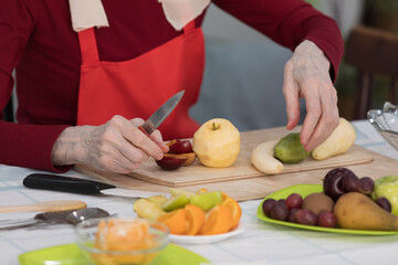 Elderly woman preparing fruit salad at home in the living room