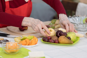 Elderly woman preparing fruit salad at home in the living room