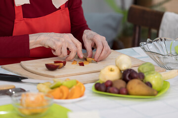 Elderly woman preparing fruit salad at home in the living room