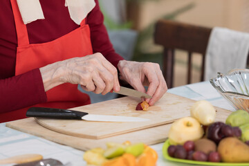 Elderly woman preparing fruit salad at home in the living room