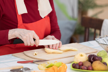 Elderly woman preparing fruit salad at home in the living room