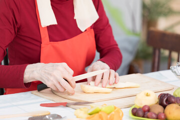 Elderly woman preparing fruit salad at home in the living room