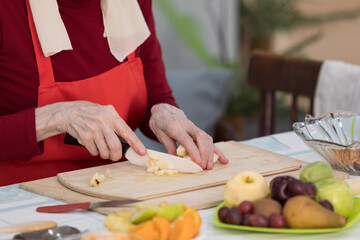 Elderly woman preparing fruit salad at home in the living room