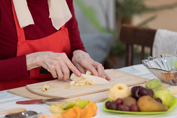 Elderly woman preparing fruit salad at home in the living room