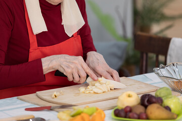 Elderly woman preparing fruit salad at home in the living room