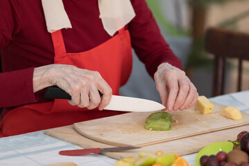 Elderly woman preparing fruit salad at home in the living room
