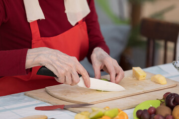 Elderly woman preparing fruit salad at home in the living room