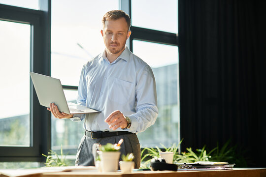 Young businessman engaged in work at modern office setting with natural light streaming in