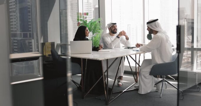 Happy Arabic business colleagues talking at large meeting table