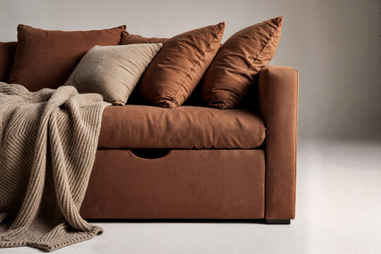 A storage daybed finished in terracotta-colored linen and topped with wool pillows and a knit blanket.