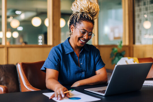 Smiling businesswoman working at a laptop in a casual office environment