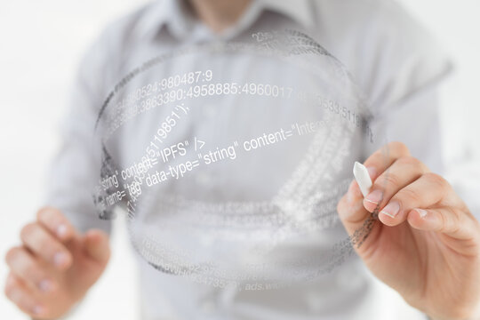 A person writes code using a marker on a transparent sphere, representing data and programming.