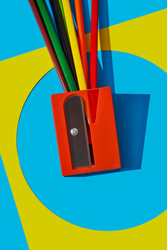 Red pencil sharpener with colored pencils on abstract background