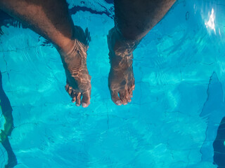 Bare feet dangling over the edge of the pool. This serene setting captures the essence of summer relaxation during a refreshing vacation.