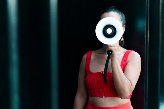 Woman in red outfit shouting into megaphone outside black building