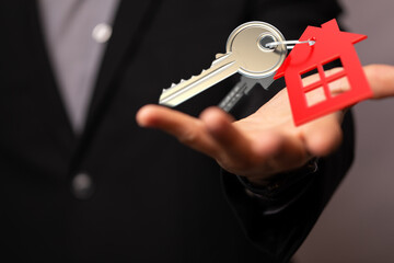 Image of a real estate agent offering house keys, symbolizing homeownership and new beginnings.