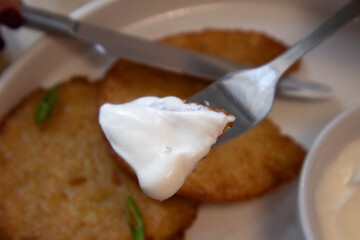 draniki on a white plate with sour cream