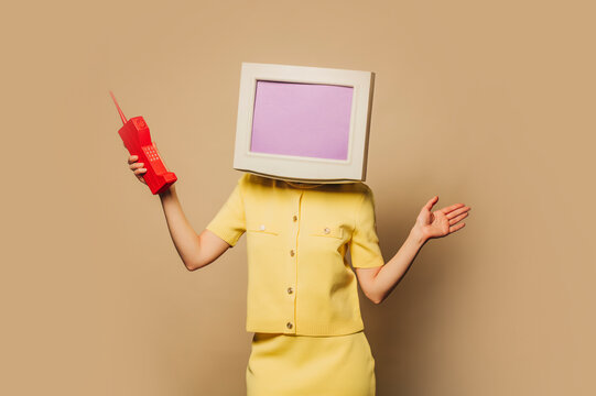 Businesswoman with PC monitor head and retro cell phone in yellow suit