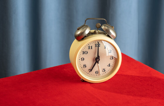 Vintage alarm clock on red table with corduroy curtain background