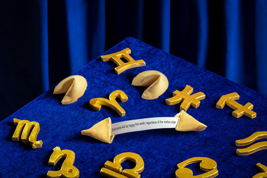 Fortune cookies and zodiac signs humorously arranged on blue velvet