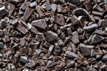 Pile broken dark chocolate bar on background, closeup, top view,. Sweet food