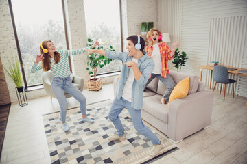 Three friends enjoying music together in a bright living room on a cheerful day, showing leisure and happiness
