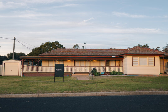 Auction sign in front yard of large weatherboard home in country town