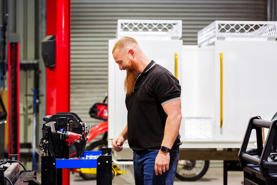 Aussie mechanic stands near machinery inside workshop