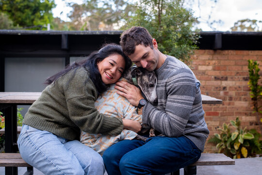 30something couple hugging their dog