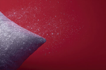 Soft pillow with gentle snow like particles floating in air, creating dreamy holiday atmosphere against vibrant red background, evoking sense of calm and comfort