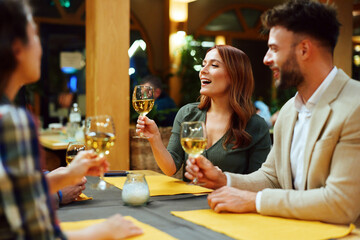 Friends enjoying wine and socializing in restaurant during evening gathering