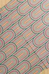 two sheets of decorative scrapbook paper with cascading or overlapping rounded motifs on wood