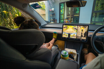 Little asian boy and girl kids enjoy play car screen entertainment and game in car park