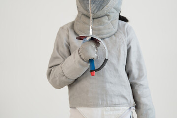 Asian girl in fencing costume with fencing sports mask and holding sword for practicing and training in gym. Teen girl fencer athlete fencing training in classroom