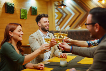 Friends toasting wine glasses in restaurant celebrating friendship