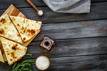 Italian focaccia with cheese and rosemary on dark wooden background top-down copy space