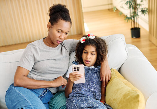 Portrait of mother and daughter having fun with a smart phone at home, family life, parenting, love and bonding concepts - Powered by Adobe