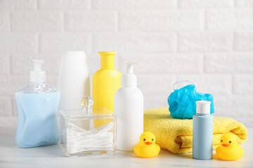 Many different baby bathroom necessities on table near brick wall