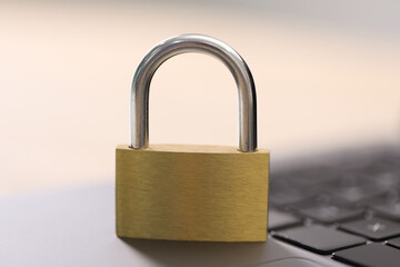 Naklejka premium Cyber safety. Metal padlock on laptop against blurred background, closeup