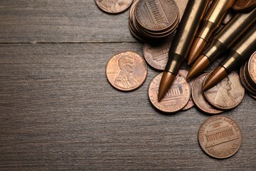 Firearm cartridges and coins on wooden table, flat lay. Space for text