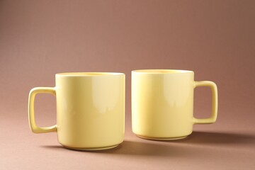 Obraz na płótnie Canvas Promotion. Two yellow mugs on brown background