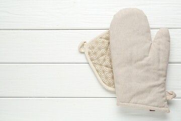 Oven glove and potholder on white wooden table, top view. Space for text
