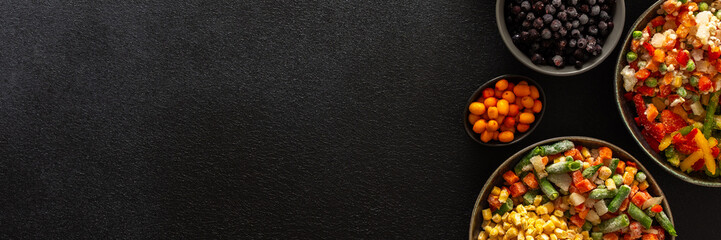 Frozen fruits and vegetables in plates, against a dark backdrop, reflecting the seasonal process of storing fresh produce for the colder months, banner