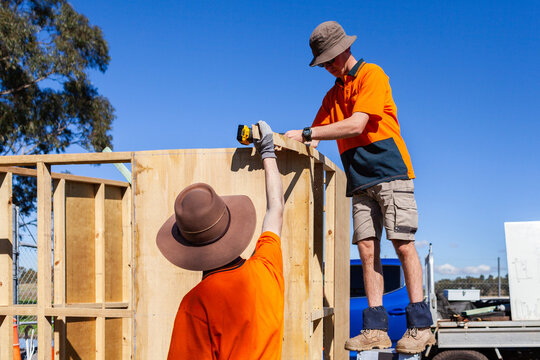 Trade apprentices learning hands on while constructing ticket booth in bright Australian sunlight