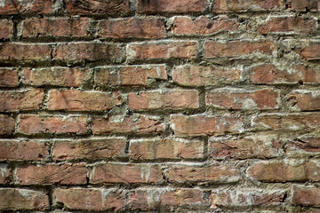 Closeup view of a weathered red brick wall with visible mortar lines
