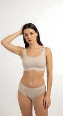 Fototapeta premium Young Woman Wearing Nude Lingerie Standing in Studio with Neutral Background