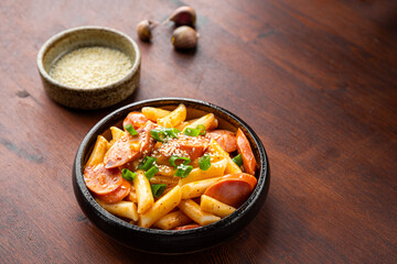 Korean street food, tteokbokki with sausages and sesame on the table