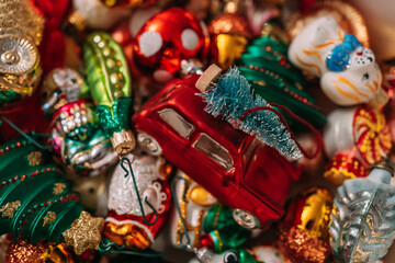 Collection of colorful Christmas ornaments, including a red car with a mini Christmas tree on its roof, surrounded by festive decorations creating a joyful holiday spirit