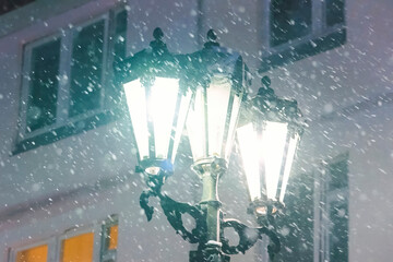 Three lampshades of street lamp against the background of the building in winter it snows.