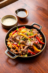 Beef stir fry in a frying pan, Asian meat with vegetables on a table vertical photo